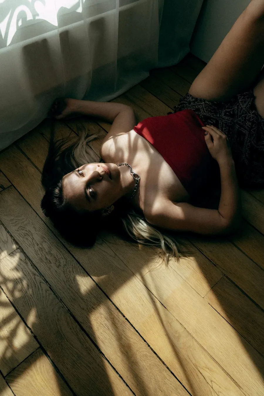 Laure lying on a wooden floor in the sunlight, looking up at the camera