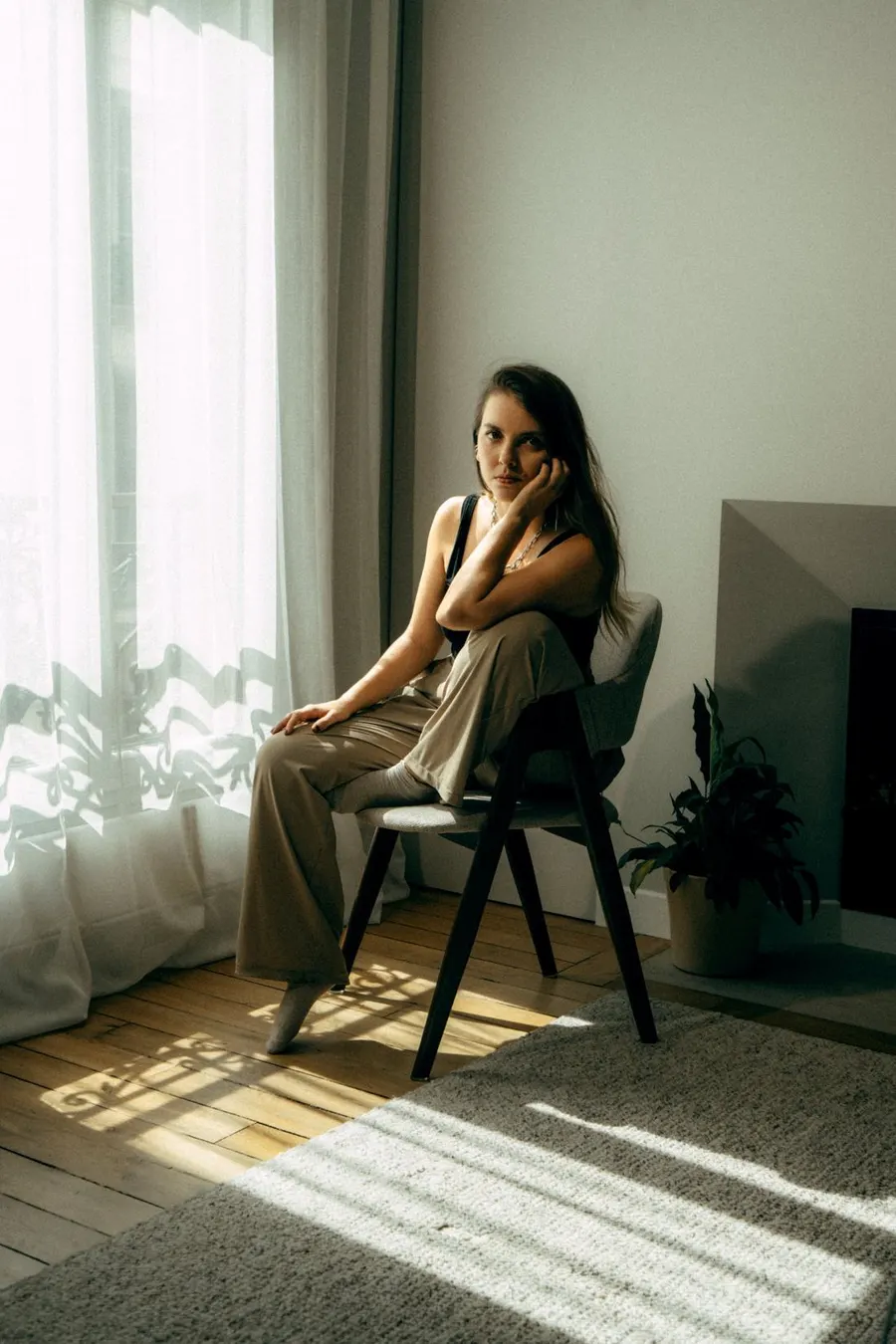 Laure sitting on a chair by a window, resting her head on her hand